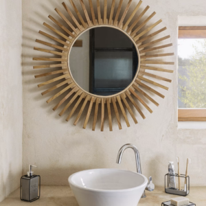 Un miroir rond Ena suspendu sur un mur, mettant en valeur sa beauté naturelle et artisanale.