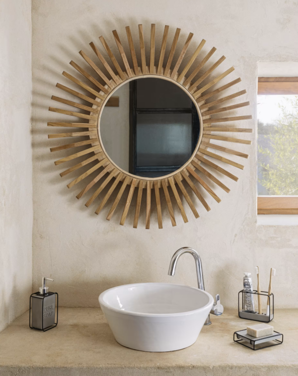 Un miroir rond Ena suspendu sur un mur, mettant en valeur sa beauté naturelle et artisanale.