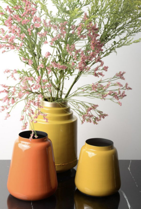 Le vase Olia en fer émaillé jaune est présenté dans un cadre lumineux, mettant en valeur sa couleur éclatante.